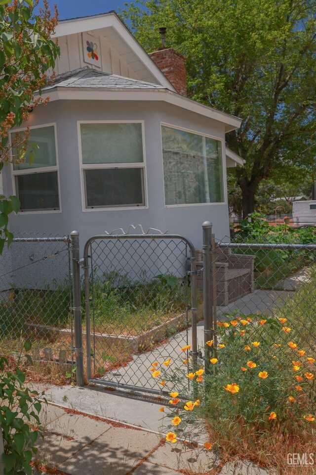 view of property exterior featuring stucco siding, a gate, fence, and a chimney