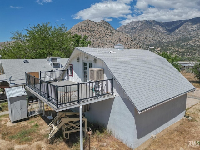 rear view of house with a deck with mountain view and central AC