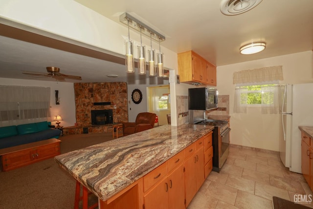 kitchen with ceiling fan, freestanding refrigerator, stainless steel microwave, open floor plan, and gas range