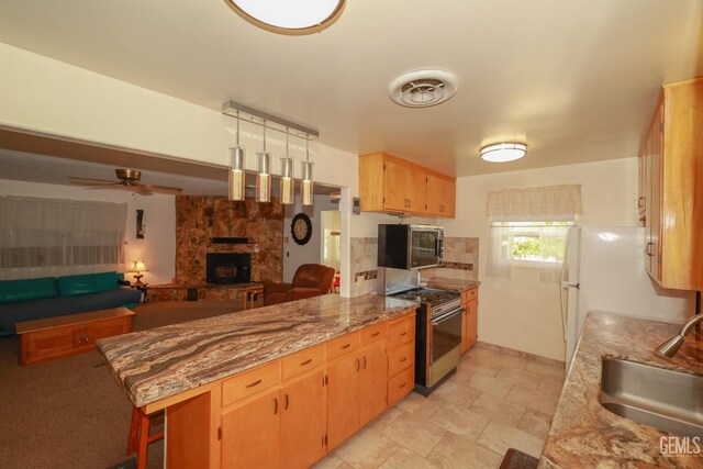 kitchen with a fireplace, open floor plan, stainless steel microwave, a sink, and gas stove
