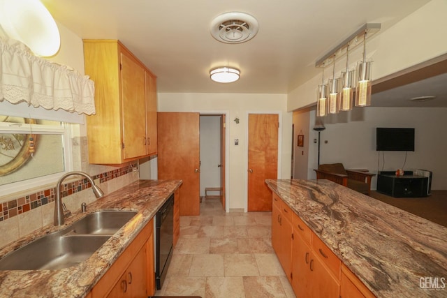 kitchen with light stone countertops, black dishwasher, tasteful backsplash, a sink, and stone finish flooring
