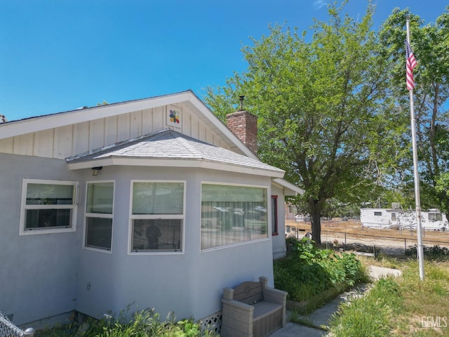 view of home's exterior with board and batten siding, fence, and a chimney