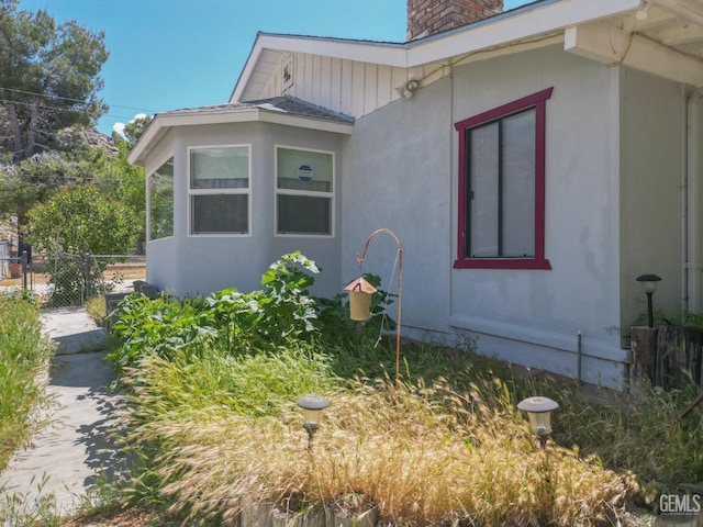 view of home's exterior with fence, a chimney, and stucco siding