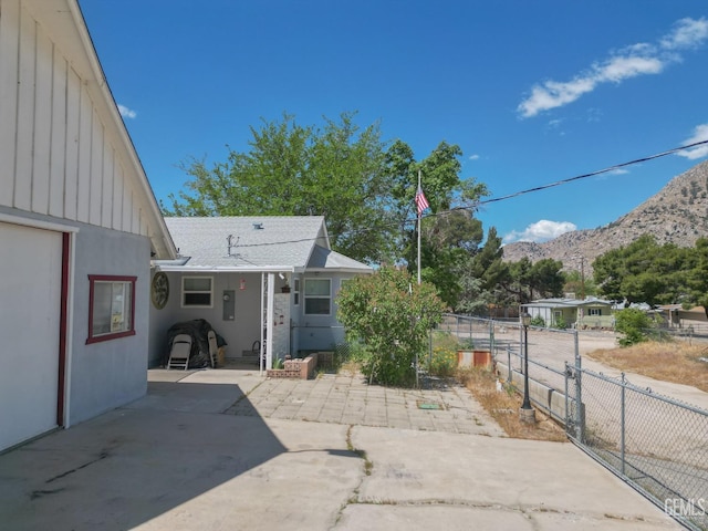 back of property with fence, a shingled roof, board and batten siding, a patio area, and a mountain view