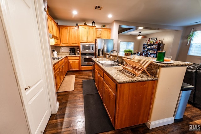 kitchen with a center island with sink, visible vents, appliances with stainless steel finishes, dark wood-type flooring, and a sink