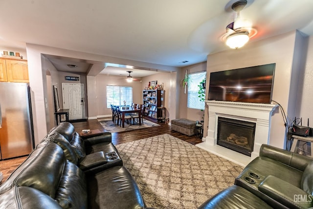 living room featuring light wood-style floors, a glass covered fireplace, ceiling fan, and baseboards