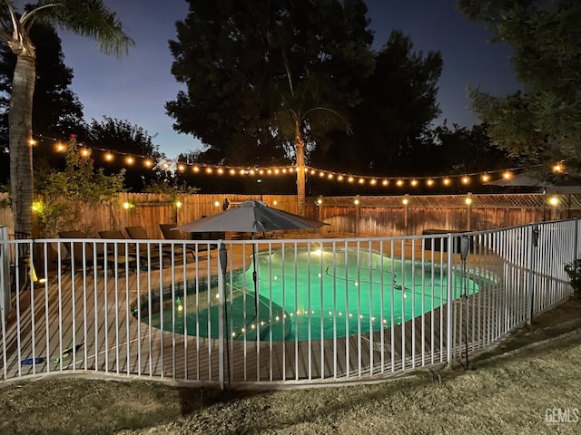 pool at night featuring a fenced backyard and a fenced in pool