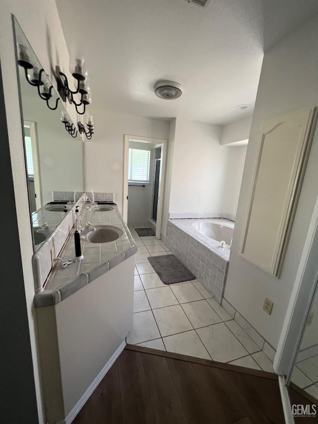 full bath with a garden tub, wood finished floors, a sink, and a shower stall