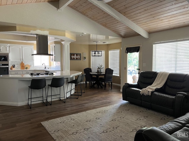 living room featuring wood finished floors, ornate columns, lofted ceiling with beams, and wooden ceiling