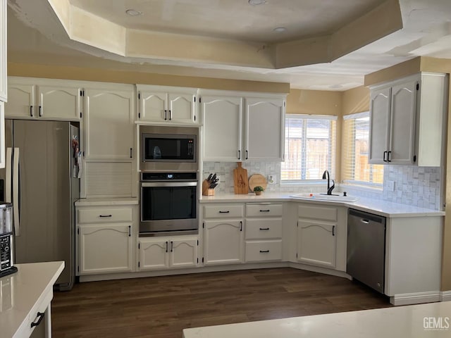 kitchen with stainless steel appliances, backsplash, a sink, and white cabinetry