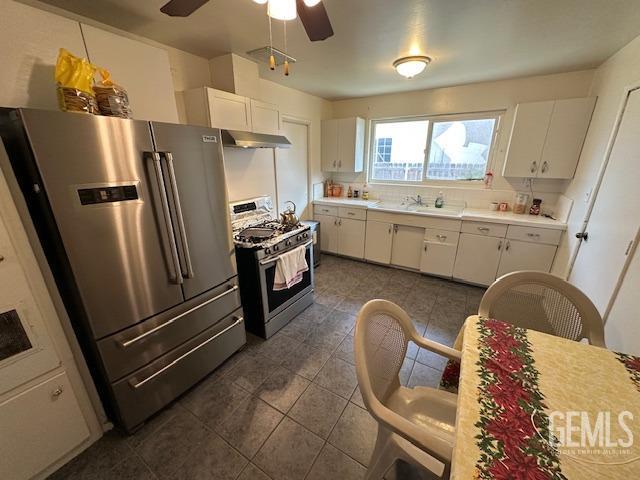 kitchen with white cabinets, dark tile patterned floors, stainless steel appliances, and ceiling fan