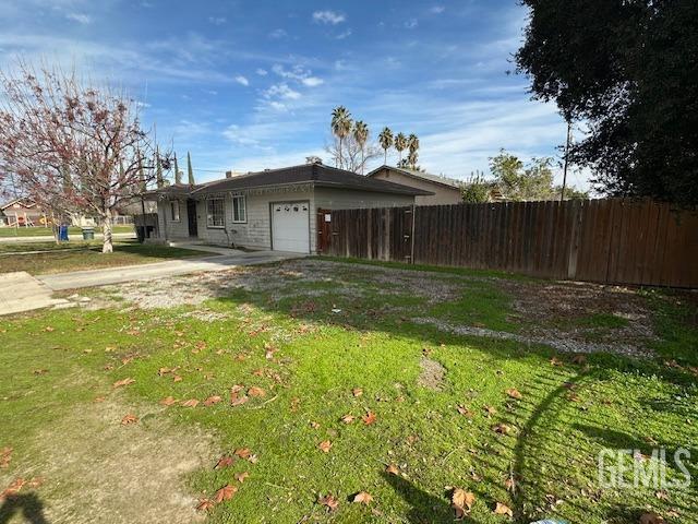 view of side of property featuring a garage and a lawn