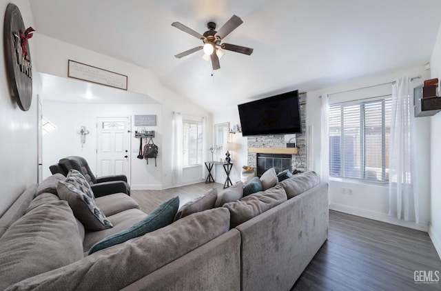 living room featuring dark hardwood / wood-style flooring, ceiling fan, a stone fireplace, and lofted ceiling