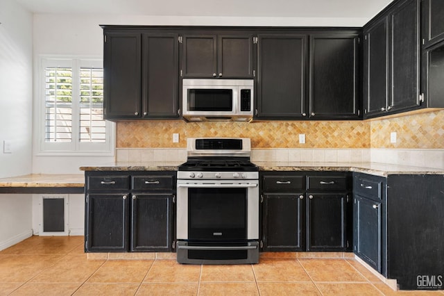 5219 Port Dr, Bakersfield, CA 93312 - kitchen featuring stainless steel appliances, dark cabinetry, light tile patterned floors, light stone countertops, and decorative backsplash