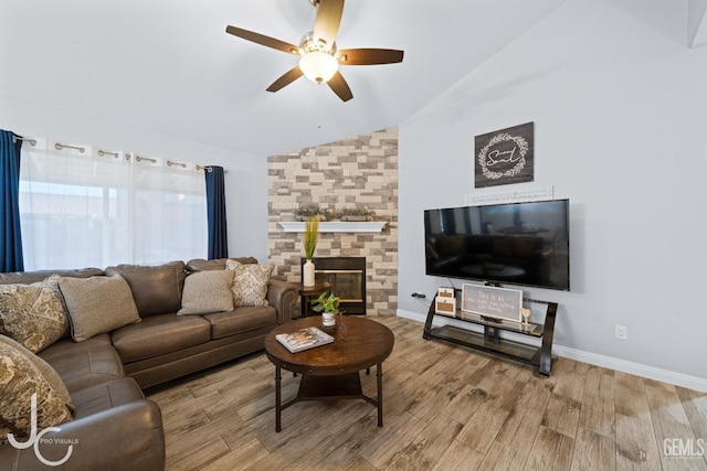 living area featuring baseboards, vaulted ceiling, a fireplace, wood finished floors, and a ceiling fan