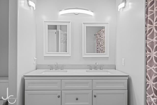 full bath with toilet, double vanity, and a sink
