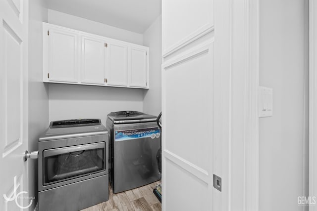 clothes washing area featuring light wood finished floors, cabinet space, and washing machine and dryer