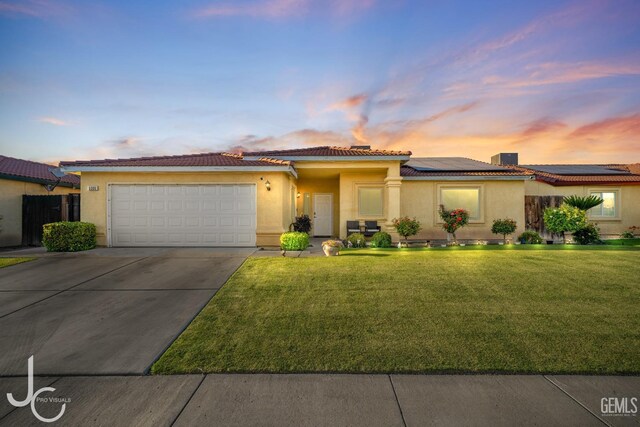 view of front facade with roof mounted solar panels, concrete driveway, a front lawn, and an attached garage