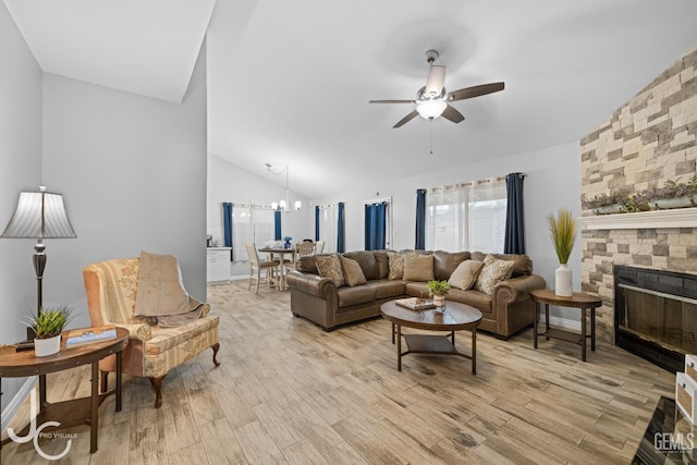 living area featuring a fireplace, light wood-style flooring, vaulted ceiling, and ceiling fan with notable chandelier