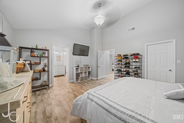 bedroom with light wood-style floors, high vaulted ceiling, visible vents, baseboards, and ensuite bathroom