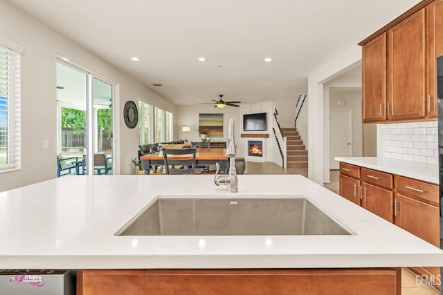 kitchen featuring a sink, ceiling fan, open floor plan, recessed lighting, and brown cabinetry