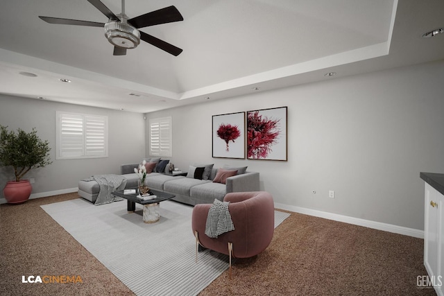 living room featuring carpet flooring, a raised ceiling, and ceiling fan