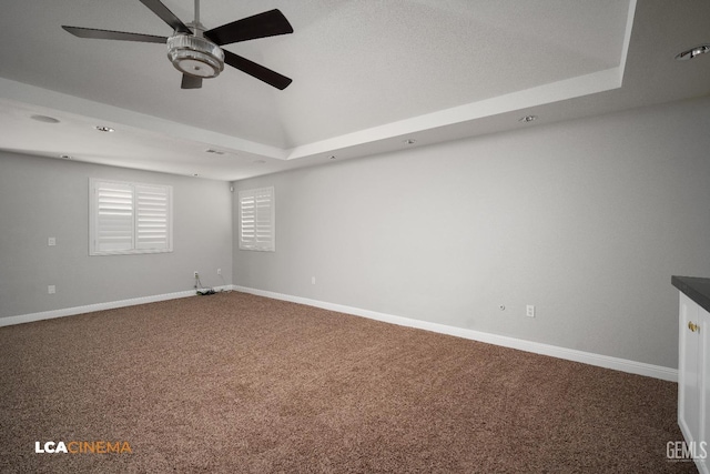 carpeted spare room with ceiling fan and a tray ceiling