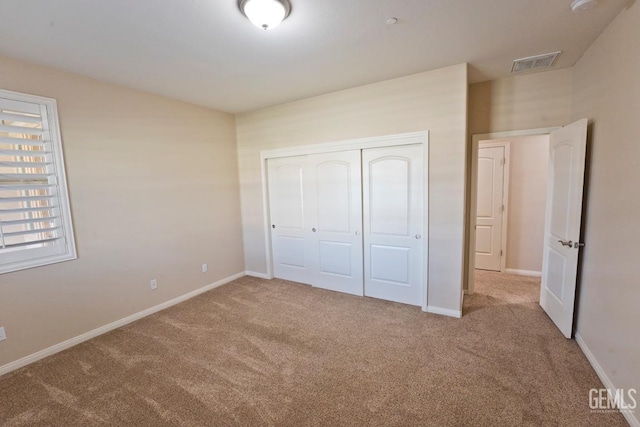 unfurnished bedroom featuring light carpet and a closet