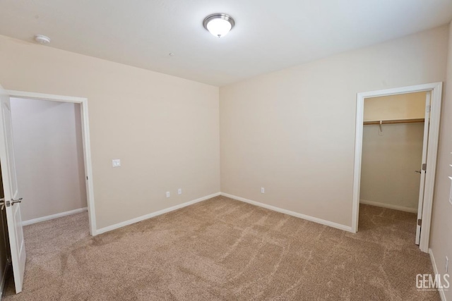 unfurnished bedroom featuring a walk in closet, light colored carpet, and a closet