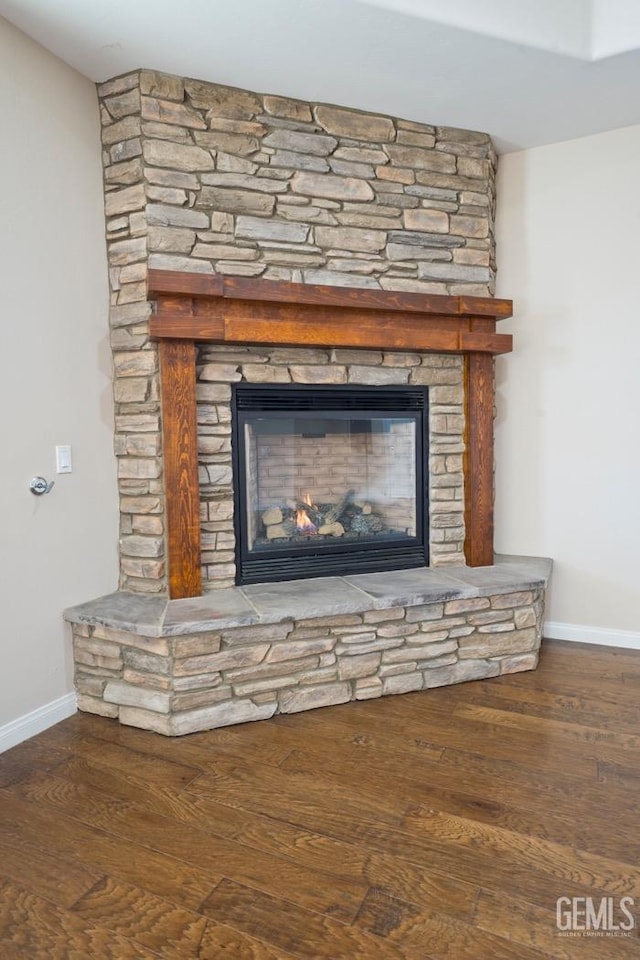 room details featuring a stone fireplace and wood-type flooring