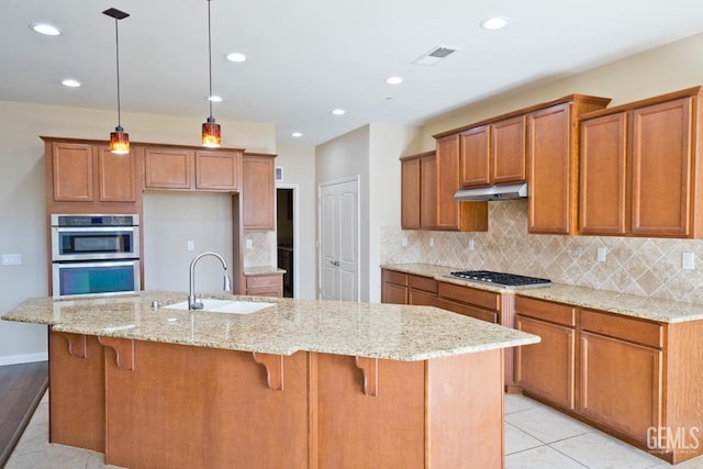 kitchen with a kitchen island with sink, sink, decorative light fixtures, and appliances with stainless steel finishes