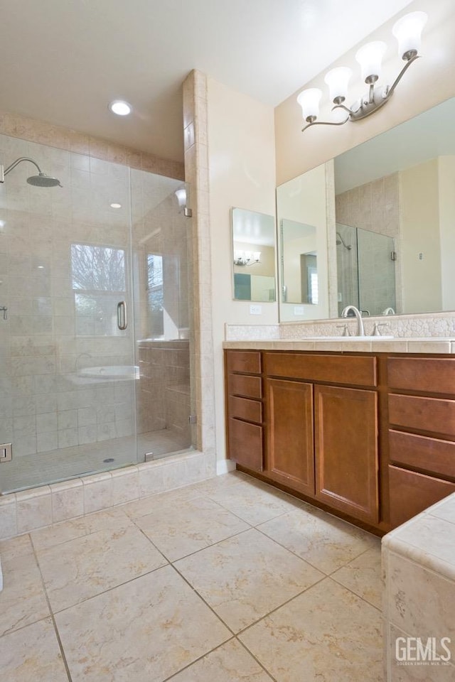 bathroom with a shower with door, vanity, and tile patterned floors