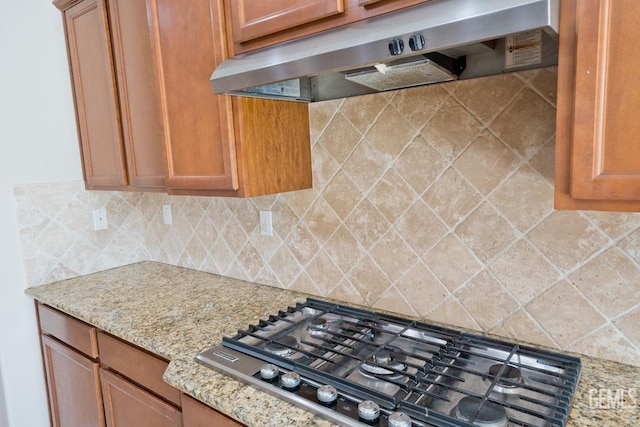 kitchen featuring light stone counters, gas cooktop, ventilation hood, and tasteful backsplash