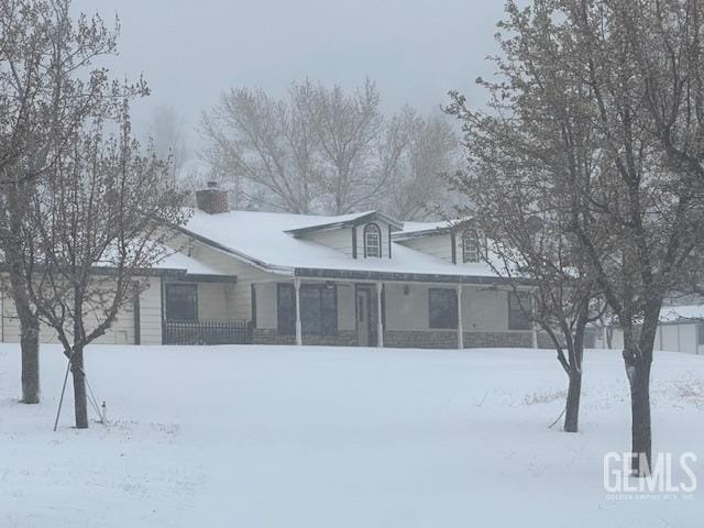 rear view of property featuring a chimney and solar panels