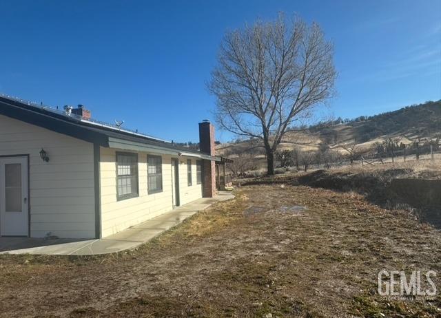 back of property featuring roof with shingles, a patio, and a chimney