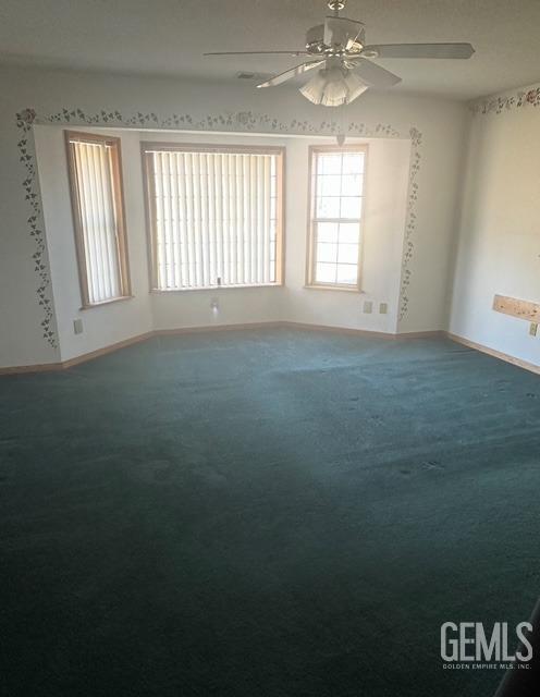 spare room featuring ceiling fan, carpet flooring, and baseboards