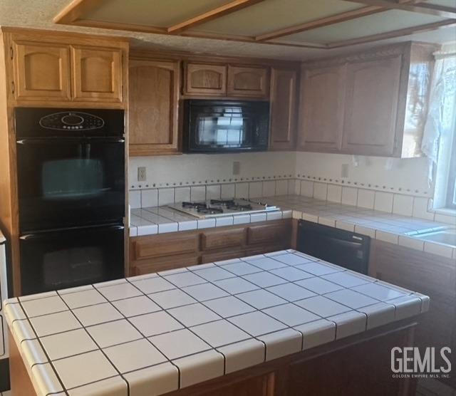 kitchen with tile counters and black appliances