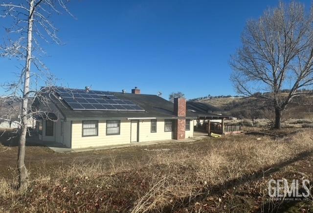 rear view of property with a chimney and solar panels