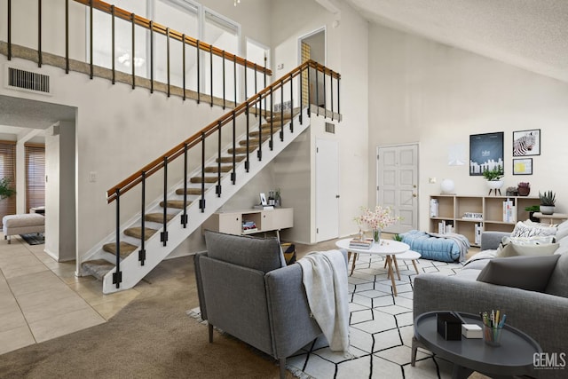 3504 Elm St, Bakersfield, CA 93301 - carpeted living room featuring high vaulted ceiling, stairway, tile patterned floors, a textured ceiling, and baseboards
