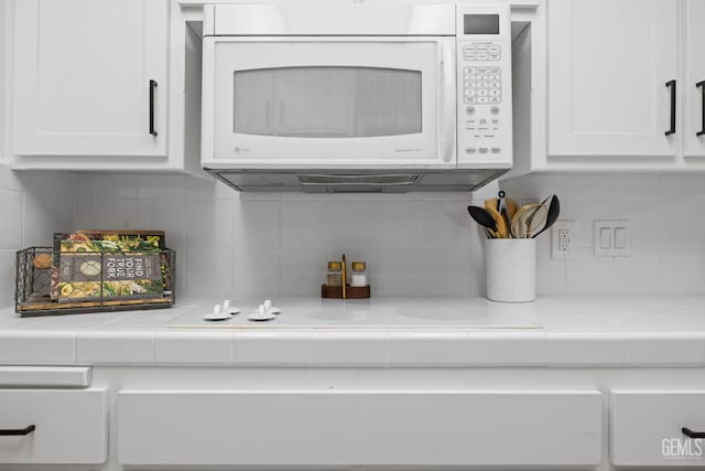 3504 Elm St, Bakersfield, CA 93301 - kitchen view of white microwave, white cabinets, tile countertops, and decorative backsplash