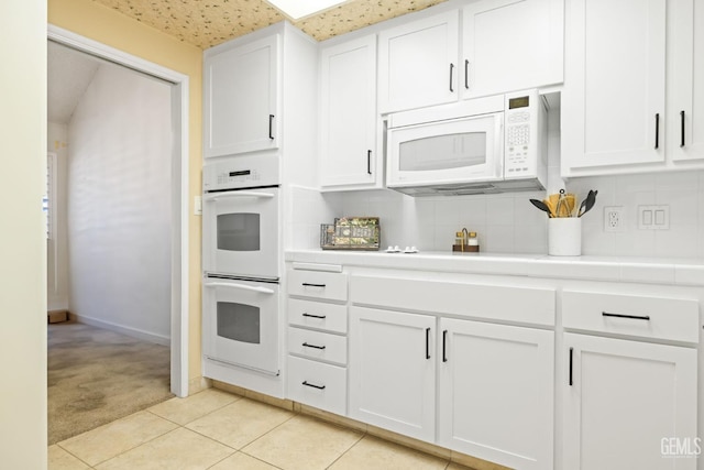 3504 Elm St, Bakersfield, CA 93301 - kitchen featuring white appliances, light carpet, tasteful backsplash, white cabinets, and light tile patterned floors