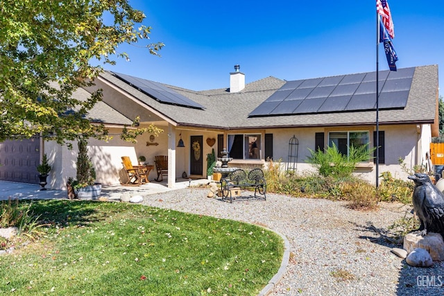 back of property featuring a yard, solar panels, and a patio