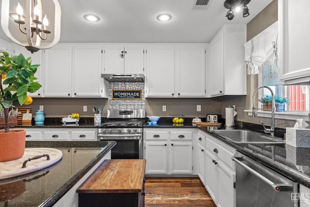 kitchen with appliances with stainless steel finishes, dark stone countertops, white cabinetry, and sink