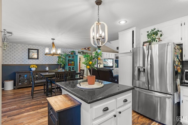 kitchen with appliances with stainless steel finishes, a kitchen island, dark wood-type flooring, white cabinetry, and a chandelier