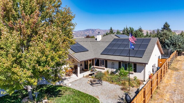 back of property featuring a mountain view, solar panels, and a patio