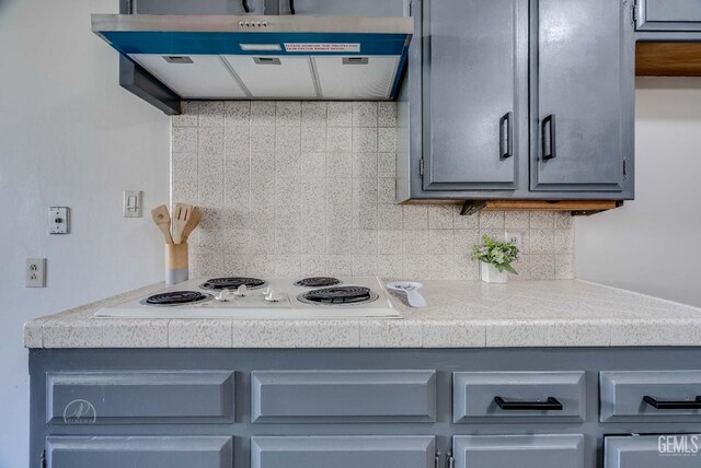 6201 Hartman Ave, Bakersfield, CA 93309 - kitchen featuring range hood, white electric cooktop, gray cabinetry, decorative backsplash, and tile counters