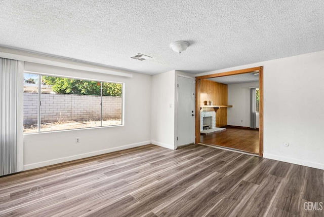 6201 Hartman Ave, Bakersfield, CA 93309 - unfurnished living room featuring a brick fireplace, wood finished floors, baseboards, and a textured ceiling