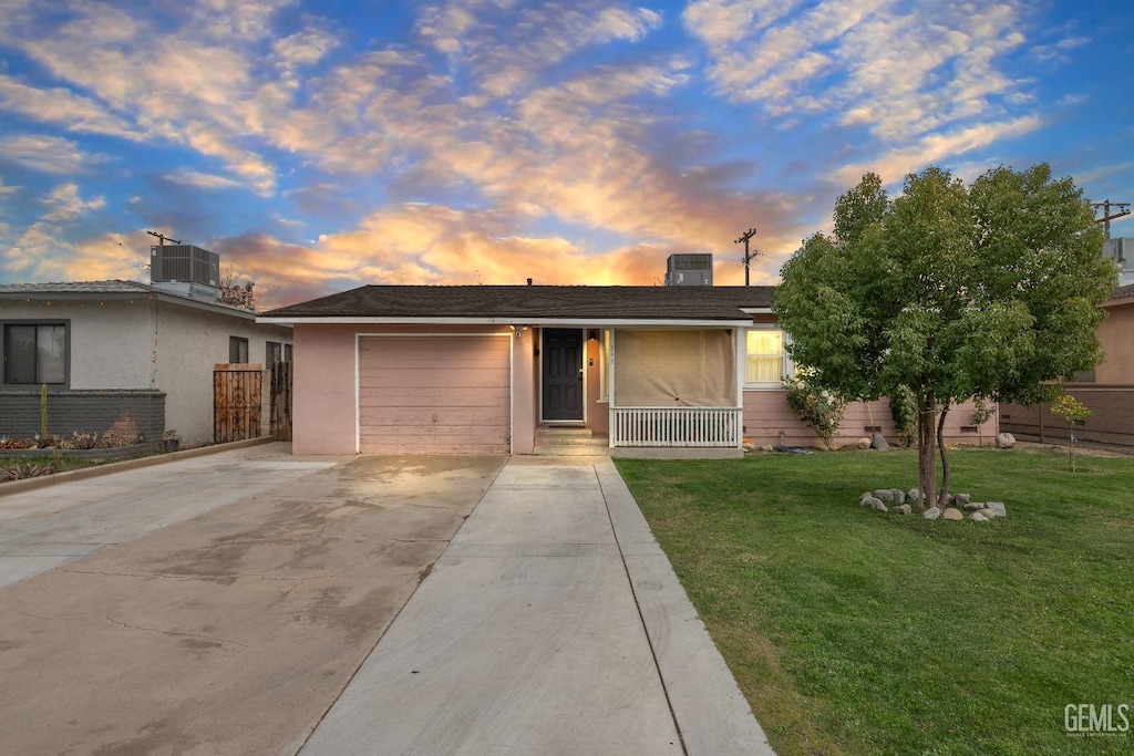 single story home with a garage, cooling unit, and a lawn