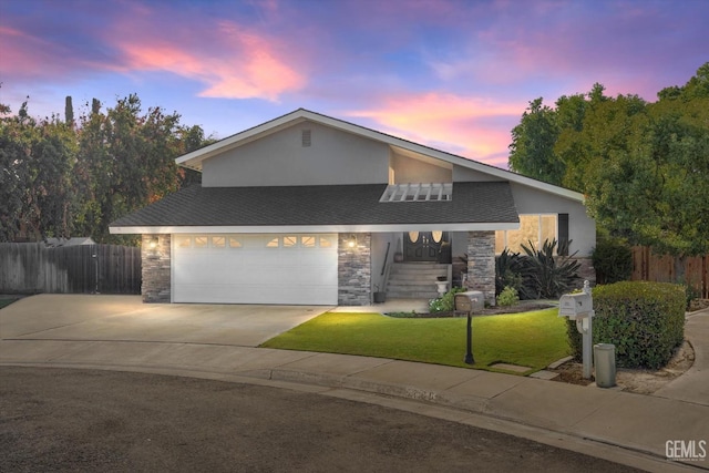 view of front facade with a garage, concrete driveway, stone siding, fence, and a yard