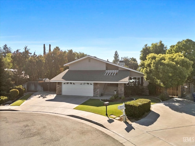 view of front facade with a garage, fence, driveway, stone siding, and a front yard